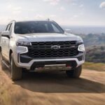 A white 2023 Chevy Tahoe z71 is shown driving off-road after winning a 2023 Chevy Tahoe vs 2023 Nissan Armada competition.