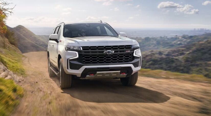 A white 2023 Chevy Tahoe z71 is shown driving off-road after winning a 2023 Chevy Tahoe vs 2023 Nissan Armada competition.