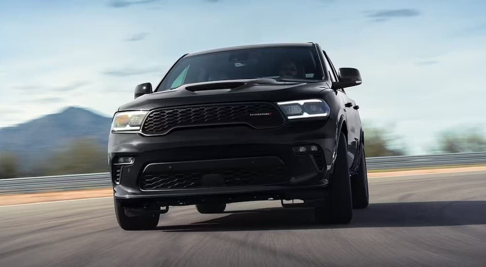A black 2023 Dodge Durango R/T Sport Utility is shown driving on a racetrack. 