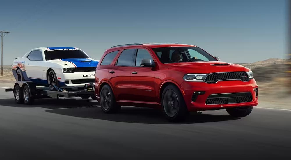 A red 2023 Dodge Durango R/T Sport Utility is shown towing a car.