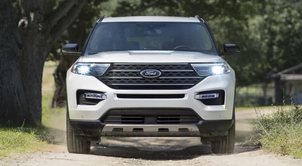 A white 2023 Ford Explorer King Ranch Edition is shown driving on a dirt road.