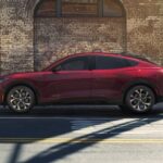 A red 2023 Ford Mustang Mach-E is shown parked on a road.
