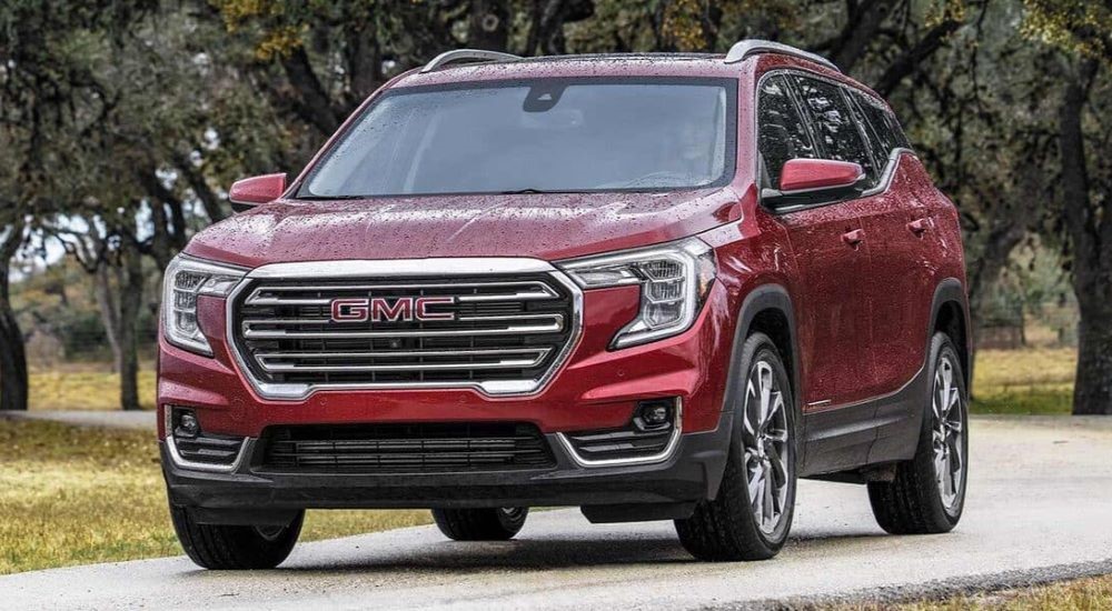 A red 2023 GMC Terrain SLT is shown parked on a wet road.