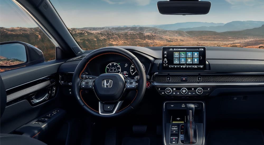 The black interior and dash of a 2023 Honda CR-V Hybrid Sport Touring is shown.