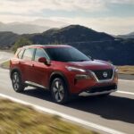 A red 2023 Nissan Rogue is shown driving on a road after winning a 2023 Nissan Rogue vs 2023 Chevy Equinox comparison.