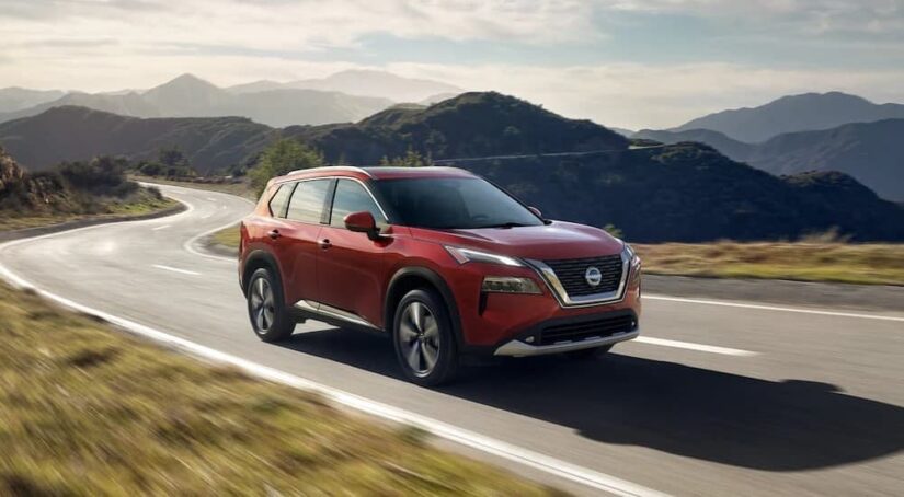 A red 2023 Nissan Rogue is shown driving on a road after winning a 2023 Nissan Rogue vs 2023 Chevy Equinox comparison.