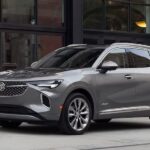 A silver 2023 Buick Envision is shown parked near a building.