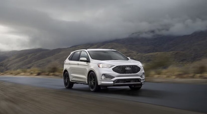 A white 2023 Ford Edge is shown driving on a road.