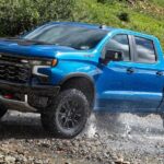 A blue 2024 Chevy Silverado 1500 ZR2 is shown driving off-road.