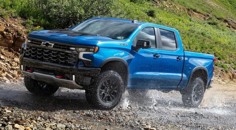 A blue 2024 Chevy Silverado 1500 ZR2 is shown driving off-road.