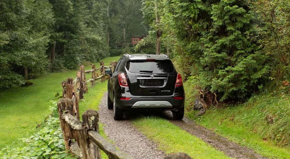 A black 2021 Buick Encore is shown driving on a dirt path.
