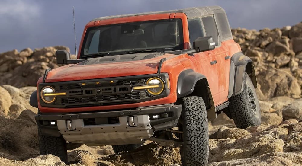 A red 2023 Ford Bronco Raptor is shown off-roading on rocks.