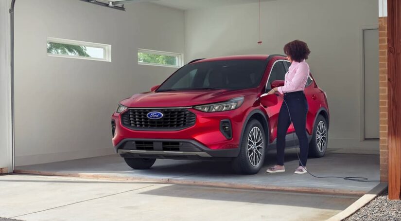 A red 2023 Ford Escape Hybrid is shown being charged in a garage.