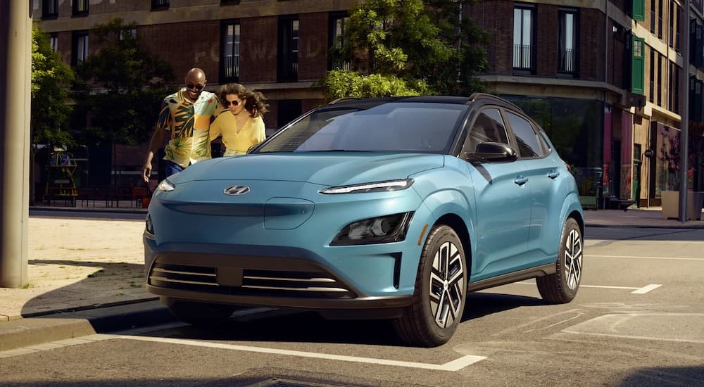 A blue 2023 Hyundai Kona Electric is shown parked on a city street.