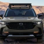 A green 2023 Mazda CX-50 is shown parked near a lake.