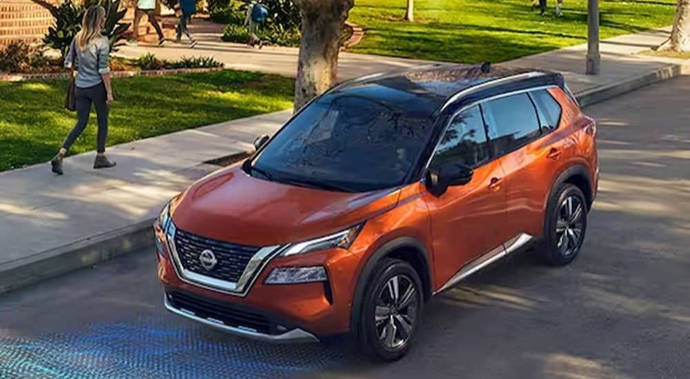 An orange 2023 Nissan Rogue is shown with simulated sensor lines on a road.