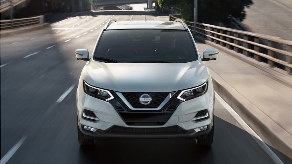 A white 2023 Nissan Qashqai is shown driving from the front.