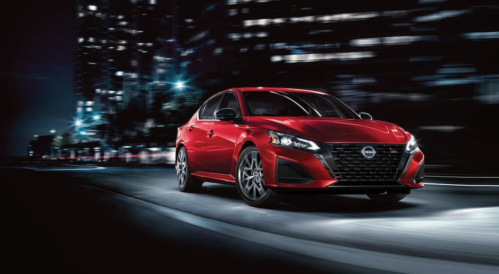 A red 2023 Nissan Altima SR is shown driving at night.