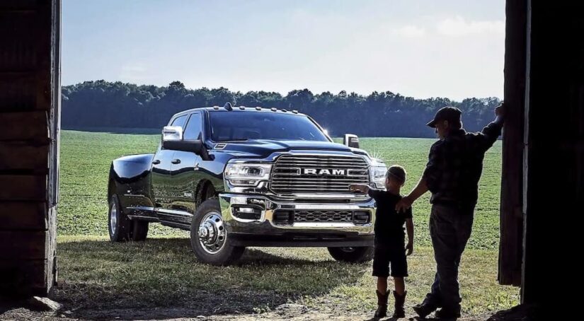 One of the most popular Ram trucks, a black 2023 Ram 3500, is shown parked on the grass near a barn.
