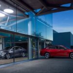 A silver and a red 2023 Chevy Malibu are shown at a dealership.