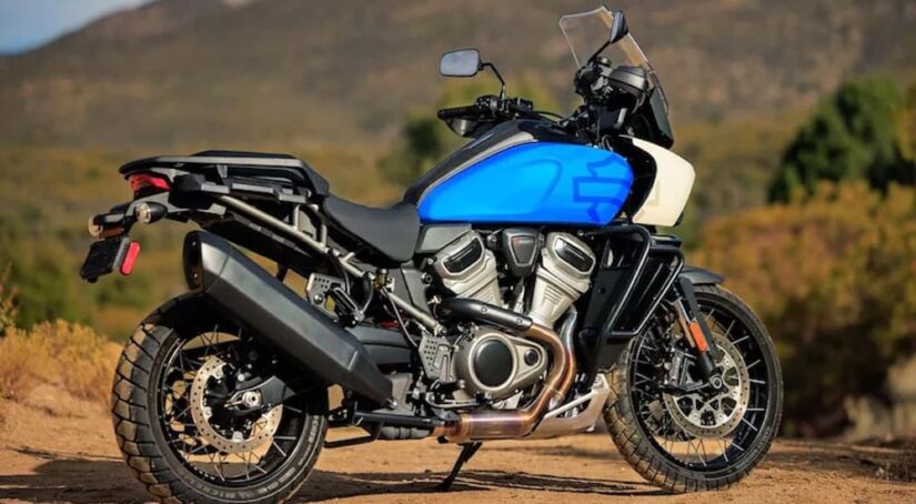 A blue 2022 Harley-Davidson Pan America is shown from the side while parked on dirt.