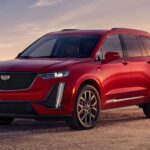 A red 2023 Cadillac XT6 is shown parked off-road.