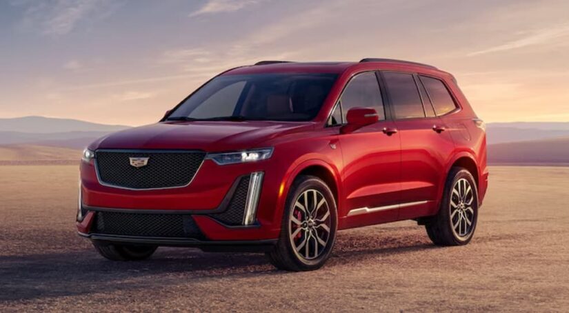 A red 2023 Cadillac XT6 is shown parked off-road.