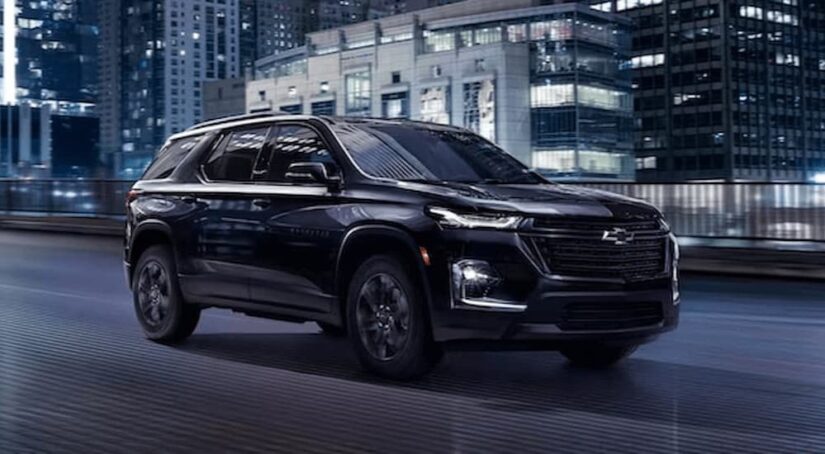 A black 2023 Chevy Traverse Midnight Edition is shown driving on a bridge after winning a 2023 Chevy Traverse vs 2023 Toyota Highlander comparison.