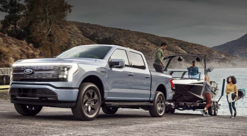 A silver 2023 Ford F-150 Lightning is shown towing a boat after winning a 2023 Ford F-150 vs 2023 Toyota Tundra comparison.