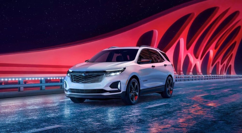 A white 2024 Chevy Equinox Redline is shown against a futuristic background.
