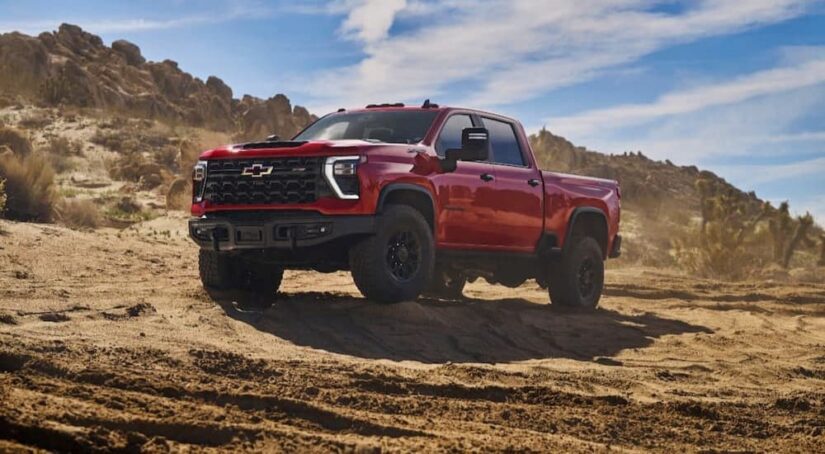 A red 2024 Chevy Silverado 2500 HD ZR2 Bison is shown parked off-road after winning a 2024 Chevy Silverado 2500 HD vs 2023 Chevy Silverado 2500 HD comparison.