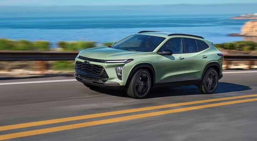A green 2024 Chevy Trax is shown driving near the ocean after winning a 2024 Chevy Trax vs 2023 Chevy Trax comparison.