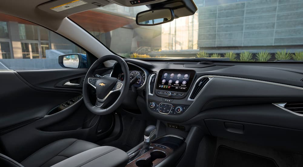 The black and grey interior of a 2023 Chevy Malibu is shown from the passenger seat after leaving a Chevrolet dealer.