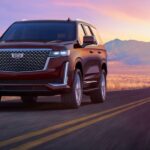 A red 2023 Cadillac Escalade is shown driving on a highway after visiting a Cadillac dealer.