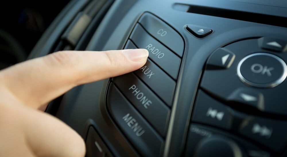 A person pressing a button on an HD radio is shown.