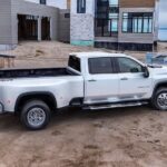 A famous Chevy Silverado for sale, a white 2024 Chevy Silverado 3500HD High Country, is shown parked on a construction site.