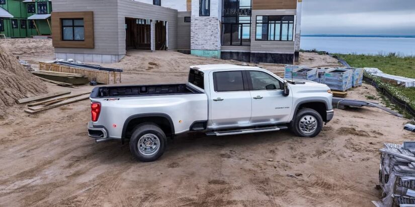 A famous Chevy Silverado for sale, a white 2024 Chevy Silverado 3500HD High Country, is shown parked on a construction site.