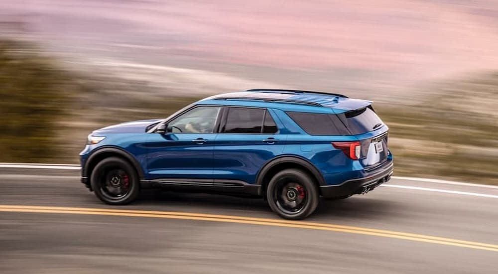 A blue 2023 Ford Explorer ST is shown driving on a highway.