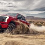 A red 2023 Ford F-150 Lightning for sale is shown kicking up dust.