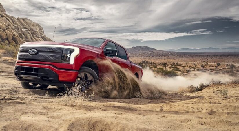A red 2023 Ford F-150 Lightning for sale is shown kicking up dust.