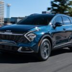 A popular Kia Sportage Hybrid for sale, a blue 2023 Kia Sportage Hybrid, is shown driving near a city.