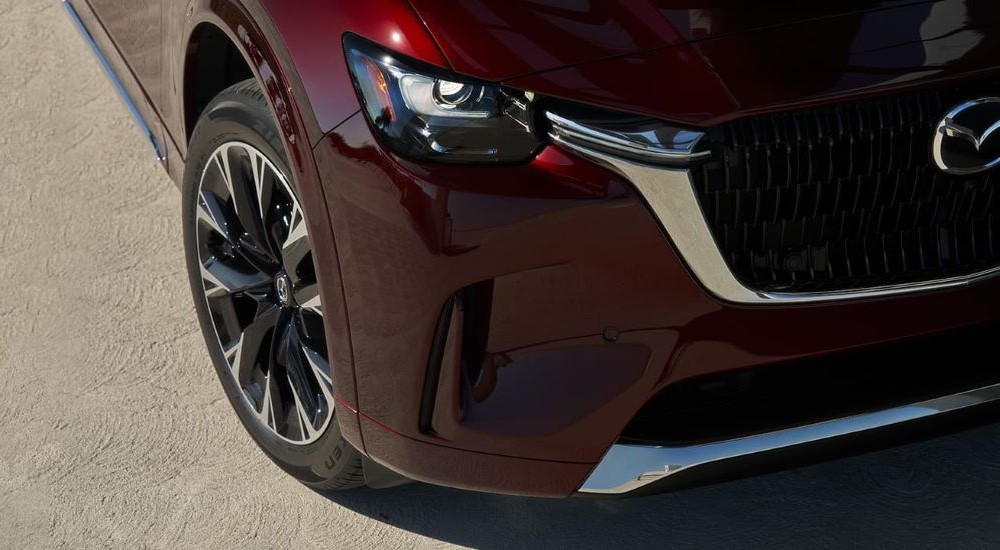 A close up shows the passenger side headlight on a maroon 2024 Mazda CX-90.