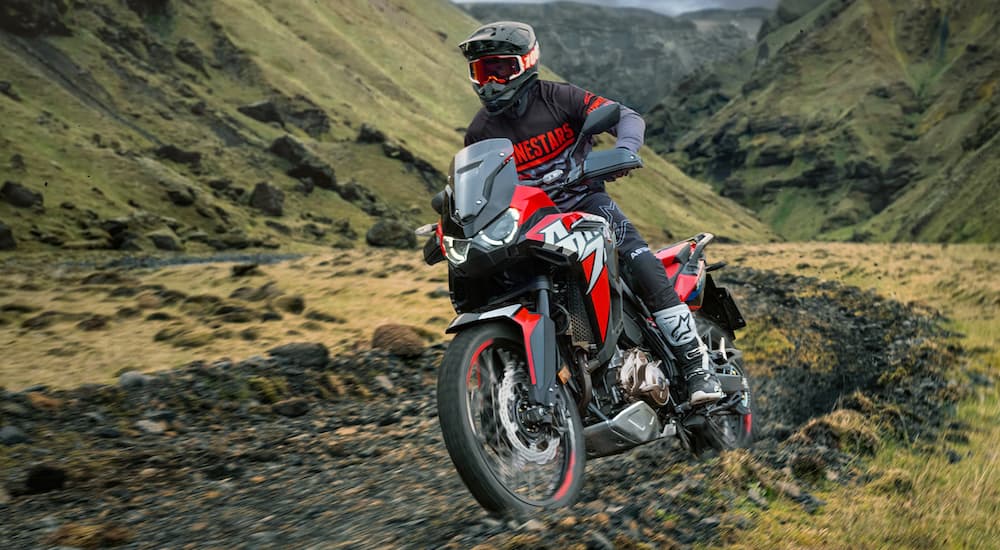 A red and black 2022 Honda Africa Twin is shown from the front at an angle while going through mud.
