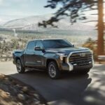 A black 2023 Toyota Tundra is shown driving on a road after visiting a Toyota dealer.
