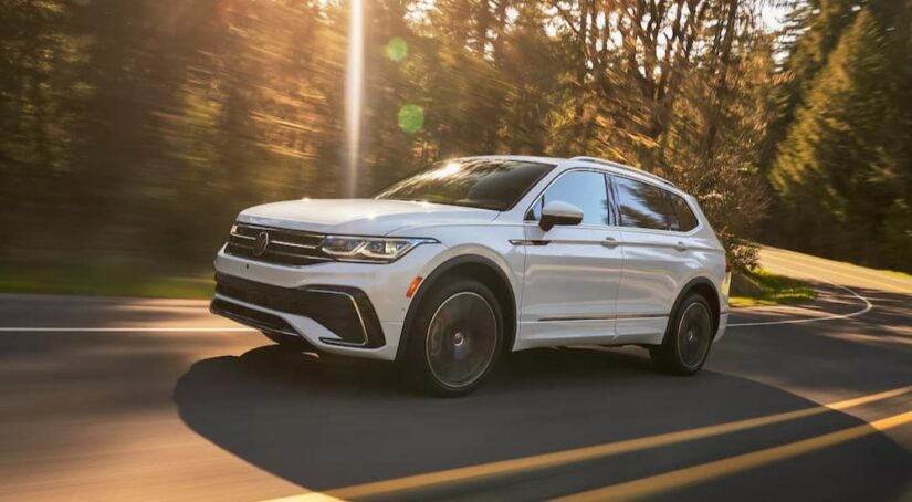 A white 2023 Volkswagen Tiguan is shown driving on a highway after visiting a VW Tiguan dealer.