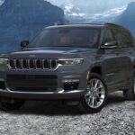 A dark gray 2023 Jeep Grand Cherokee is shown parked near a mountain range.