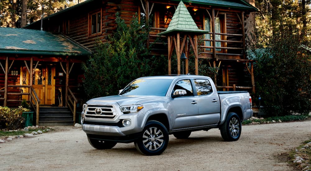 A silver 2021 GMC Canyon is shown parked near a log cabin.