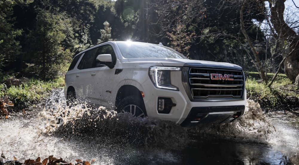 A white 2022 GMC Yukon AT4 is shown driving off-road.