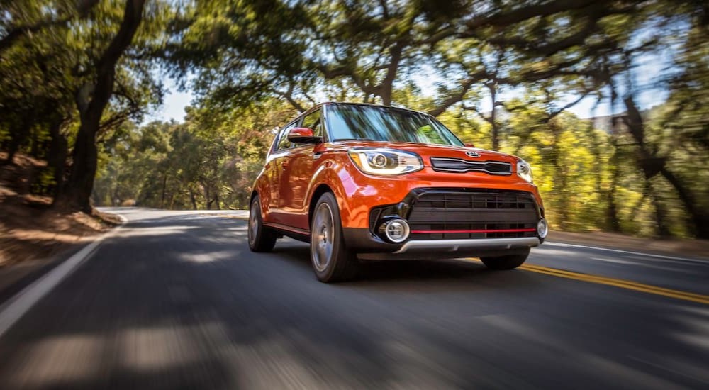 An orange 2019 Kia Soul is shown driving on a highway.