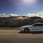 A white 2020 Toyota Supra GR is shown driving on a scenic highway.
